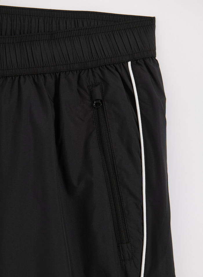 Mustat aim'n Balance Tracksuit Pants -housut vetoketjutaskulla ja valkoisella sivunauhalla.
