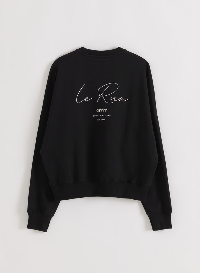 Musta Le Run Running Sweatshirt takaa nähtynä flätlay-kuvassa, jossa näkyy valkoinen Le Run -grafiikka selässä