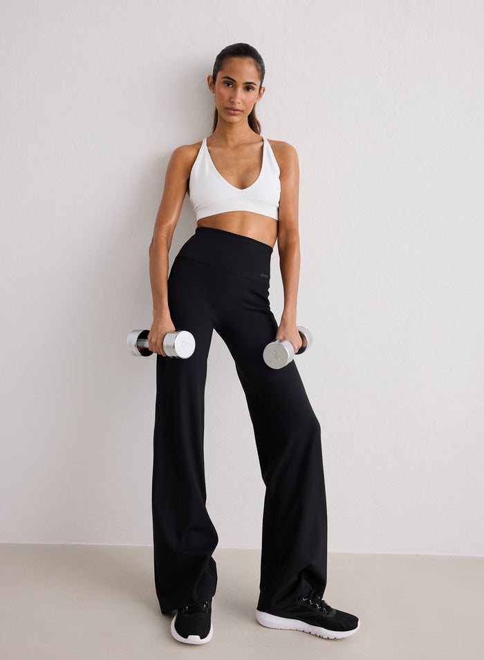 Nainen yllään valkoiset urheiluliivit ja mustat aim'n Sense Straight Leg Petite Tights -trikoot pitelemässä käsipainoja