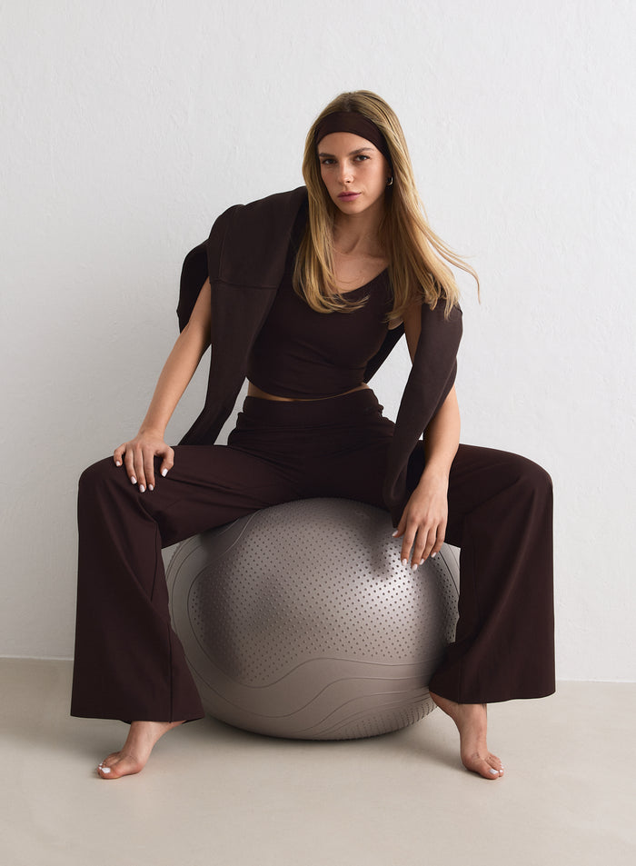 Suklaanruskeat aim'n Sense Tall Pants -housut ja toppi harmaalla jumppapallolla. [M-170cm]
