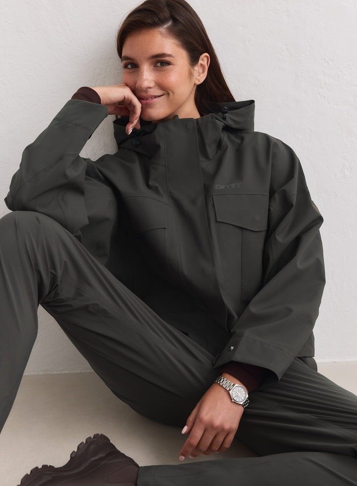 Tummanvihreä aim'n Waterproof Jacket cargo-taskuilla ja kolmikerroksisella hupulla. [M-178cm]