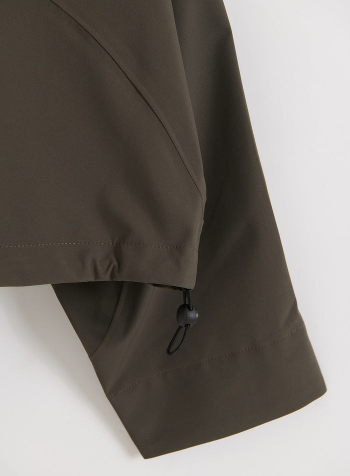 Lähikuva Dark Ivy Waterproof Jacket -takin hihan ja helman yksityiskohdasta, jossa on säädettävä kiristysnyöri