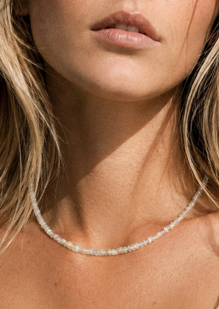 A woman wearing a beaded opal necklace.