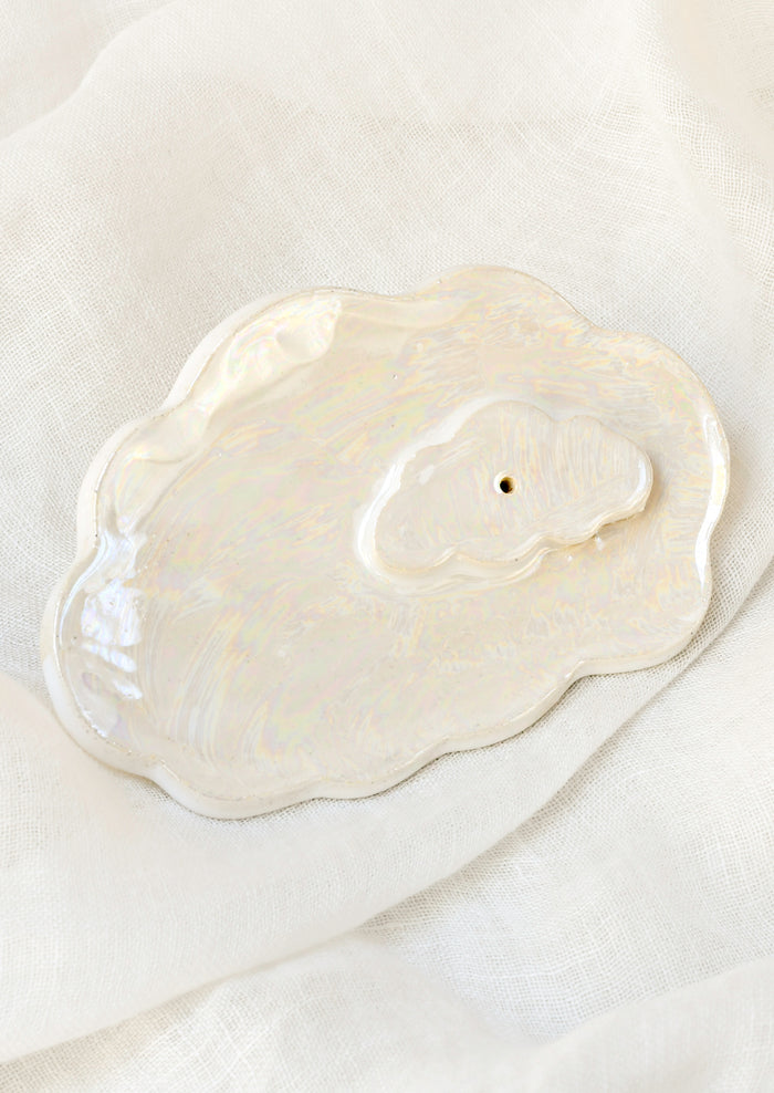 A white ceramic iridescent cloud-shaped incense holder.