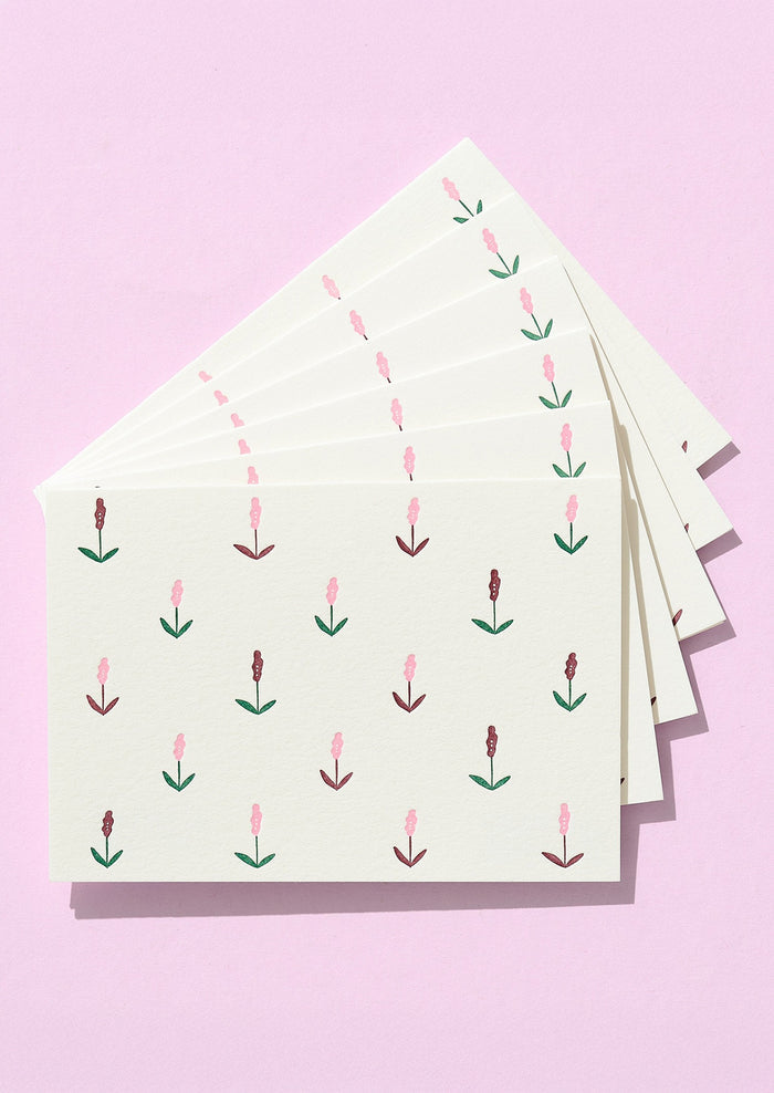 Stack of cards with floral pattern on a pink background