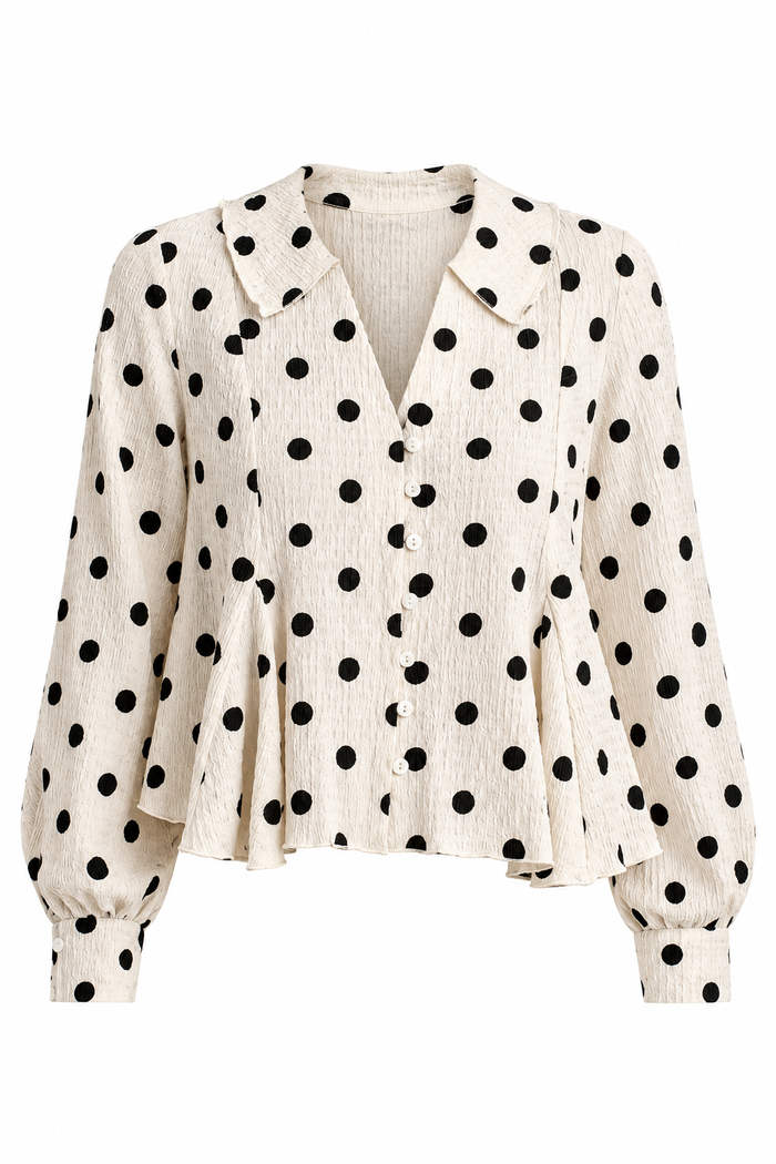 Women's cream blouse with black polka dots, a V-neckline, front buttons and long sleeves, styled with light-wash jeans.