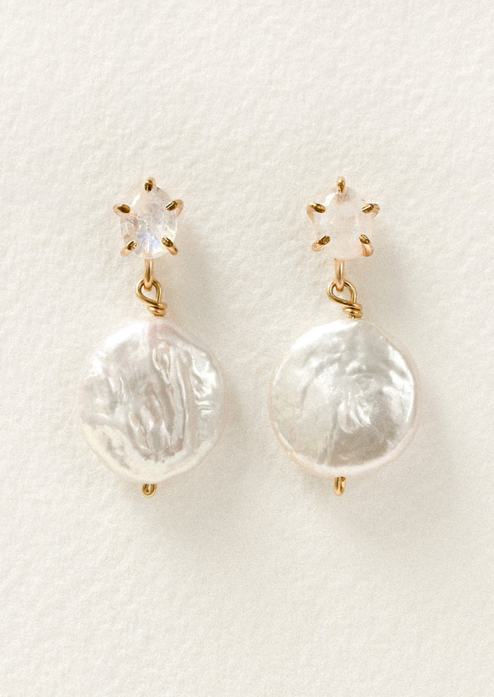 A pair of gold stud earrings feature a moonstone in a pronged setting with a large dangling freshwater coin pearl hanging below.
