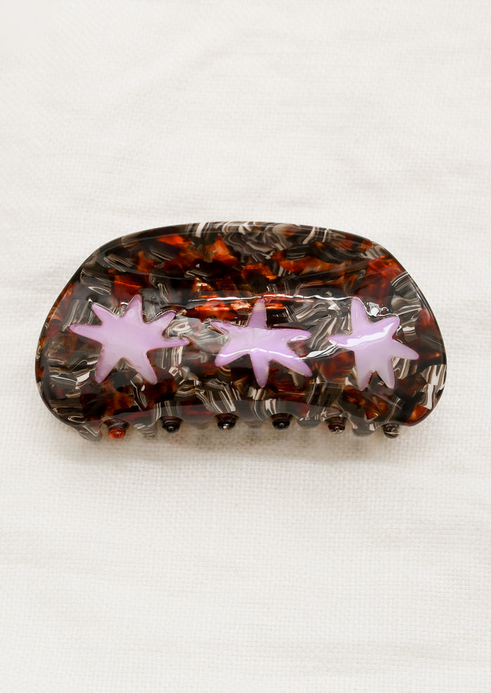 A hair claw in brown tortoise with translucent purple starburst design.