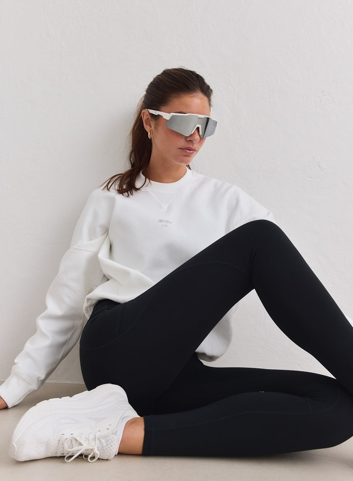 Valkoinen rento aim'n juoksu-collegepaita yhdistettynä mustiin leggingseihin ja urheilulaseihin. [M-178cm]