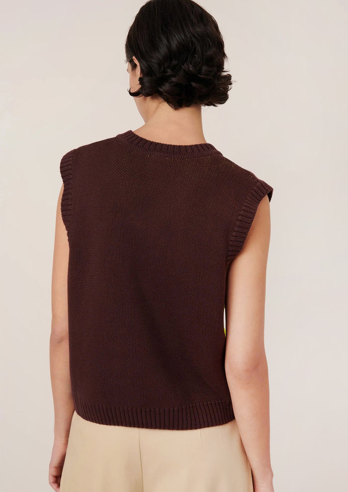 Person wearing a brown knit vest with a large yellow butterfly design.